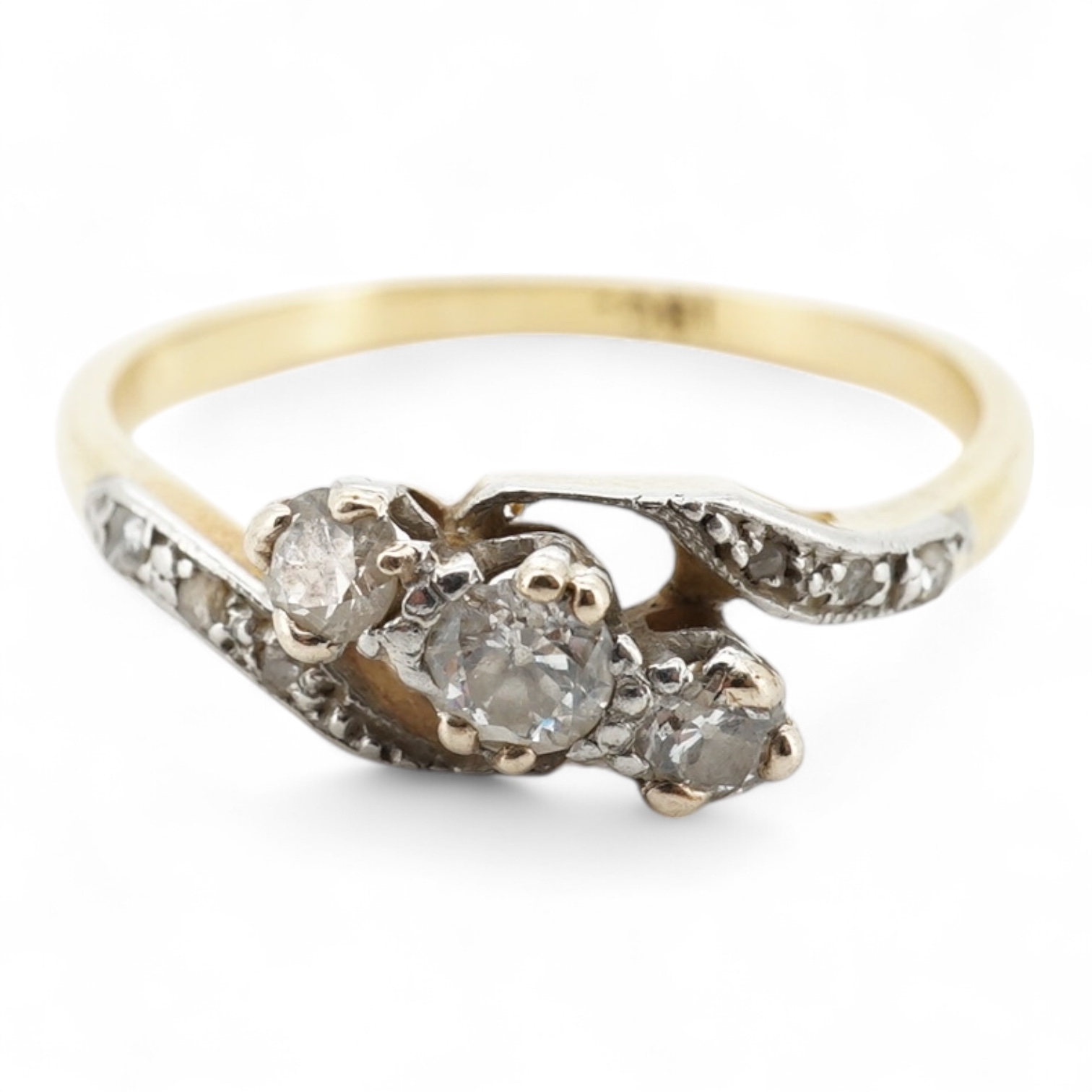A three-stone diamond ring, early 20th century, centring on a diagonal line of three circular-cut diamonds totalling approximately 0.24 carats, to asymmetrical shoulders set with smaller rose-cut diamonds, mounted in gol